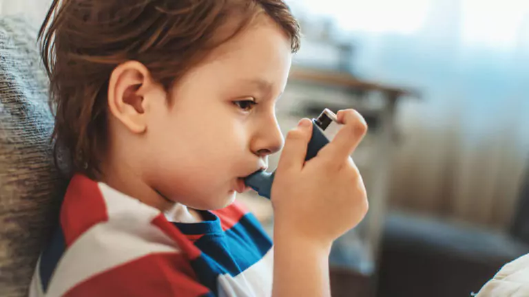 Asthmatic boy using his inhaler