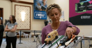 women placing a car on Melaleuca pinewood derby tract