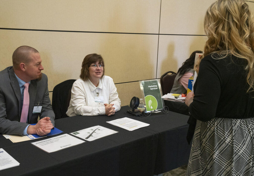 Melaleuca Team Members Josh Conrad and Susan Krieg talk to a candidate about the company’s marketing services.